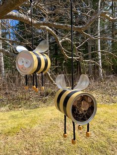 two metal bee wind chimes hanging from a tree