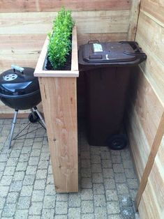 a planter with a potted plant in it next to a black bbq