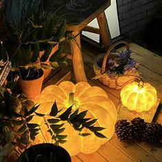 pumpkins and pine cones are lit up on the deck