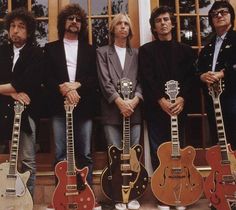 four men standing next to each other with guitars in front of them