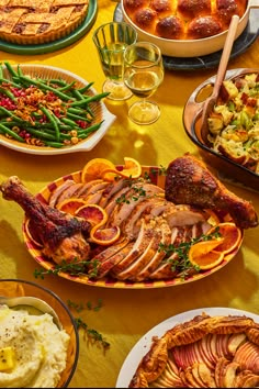 a table full of food including turkey, potatoes and green beans with bread on the side