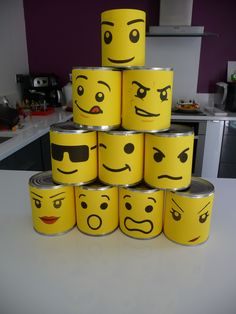 a stack of yellow canisters with faces painted on them in the shape of emoticions