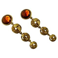 YVES SAINT LAURENT vintage gold toned dangling earrings (clip-on) featuring 3 ribbed textured ribbon-like balls topped by a large faceted orange resin crystal-like cabochon. Embossed YSL Made in France. Indicative measurements : height approx. 8.8 cm (3.46 inches) / max. diameter approx. 2.1 cm (0.83 inch). Comes with a YSL dust bag (used condition). NOTES - This is a preloved vintage item, therefore it might have imperfections. - Colors may differ slightly from actual product appearance due to differences in lighting conditions. - As a buyer, you are fully responsible for customs duties, other local taxes and any administrative procedures related to imports into the country of destination. Ysl Vintage, Orange Resin, Saint Laurent Vintage, Vintage Fall, Dangling Earrings, Vintage Gold, Made In France, Clip On Earrings, Yves Saint Laurent