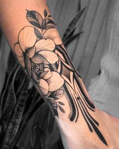 a woman's arm with flowers and leaves on the side of her body, in black and white