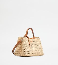 the straw bag is made from natural materials and has two handles, one with a leather handle