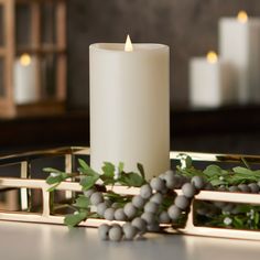 a white candle sitting on top of a table next to some silver and green decorations