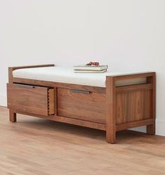 a wooden bench sitting on top of a hard wood floor next to a white wall