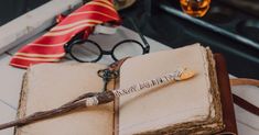 an open book sitting on top of a table next to some glasses and a tie