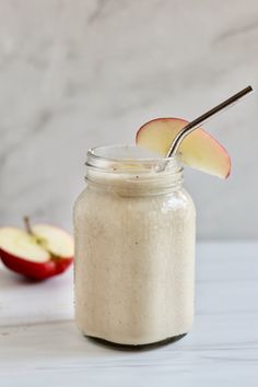 a glass jar filled with oatmeal next to an apple