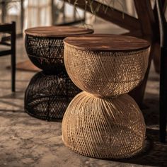 three wicker stools sitting next to each other on the floor in front of a wooden table