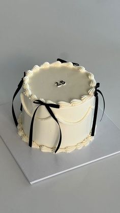 a white cake sitting on top of a silver plate with black ribbon around the edge