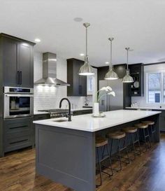 a large kitchen with wooden floors and gray cabinets