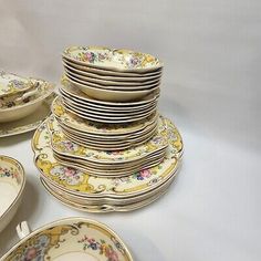 a table topped with lots of plates covered in floral designs on top of each other