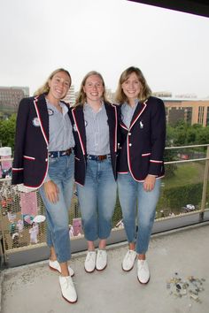 three women standing next to each other on a balcony