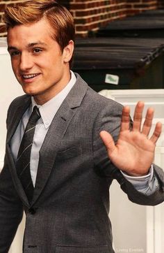 a young man in a suit and tie making a hand gesture with his right hand