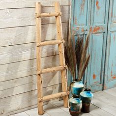 three vases and a ladder are sitting on the floor