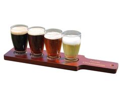 four different types of beer in glasses on a wooden tray with a name plate and plaque