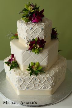 a three tiered wedding cake with flowers on top