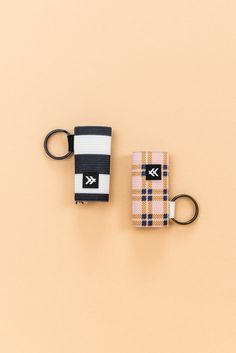 two keychains are sitting next to each other on a beige surface, one has a black and white stripe