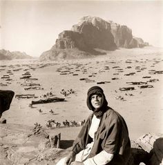 an old photo of a man sitting on rocks in the desert