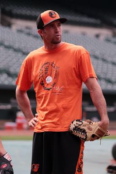 a man in an orange shirt is holding a catchers mitt