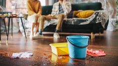 two people sitting on a couch in the living room, one is cleaning the floor