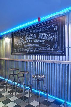 an empty restaurant with three stools and a chalkboard sign on the wall behind it