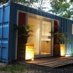 a blue shipping container with its doors open and plants in the corner on top of it