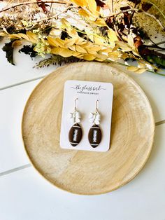 a pair of earrings sitting on top of a wooden plate