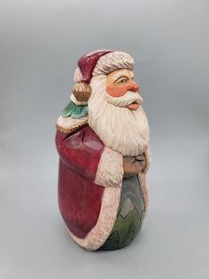 a ceramic santa clause figurine sitting on top of a table next to a gray background