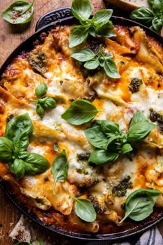 a casserole dish with spinach, cheese and sauce on a wooden table