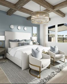 a large bed sitting in a bedroom under a chandelier next to two chairs