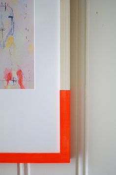 an orange and white painting hanging on the wall next to a door frame with a red border