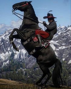 a man riding on the back of a black horse in front of snow covered mountains