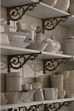 the shelves are filled with white dishes and cups on them, along with other kitchen items