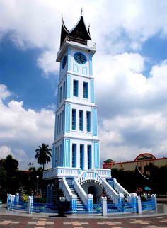 a large white and blue clock tower with steps leading up to it's top