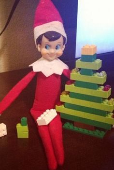 an elf is standing next to a lego christmas tree