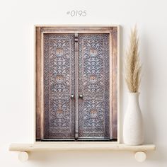 a white vase sitting on top of a shelf next to a wooden door with intricate designs