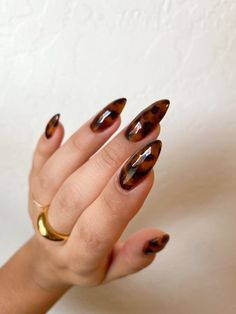 a woman's hand with some brown and black nail polish on her nails,