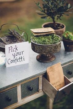 a table topped with lots of potted plants next to a sign that says pick your confetti