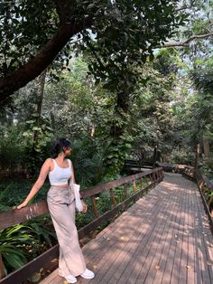 a woman is standing on a wooden bridge