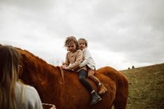 two children sitting on the back of a brown horse