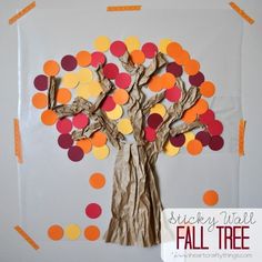 a tree made out of brown paper with orange and red circles on it, sitting in front of a white background