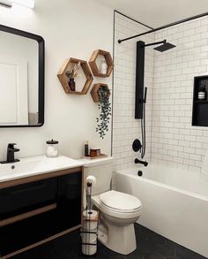 a bathroom with black and white tile, hexagonal mirror, sink, toilet and bathtub