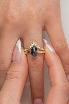 a woman's hand with two rings on top of her fingers and one has a black diamond in the middle