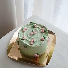 there is a green cake with pink flowers on it