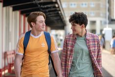 two young men walking down the street holding hands and looking into each other's eyes