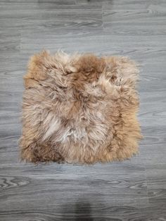 a brown and white sheepskin rug sitting on top of a wooden floor