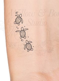 a small turtle tattoo on the back of a woman's arm