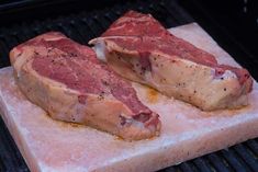 two raw meats sit on top of the grill